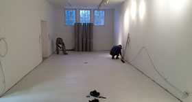 2 Männer arbeiten in einem leeren Raum.