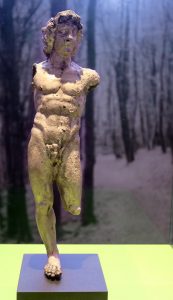 Replik einer Bronze Statuette, die Figur steht auf dem rechten Bein. Beide Arme fehlen ab der Schulter und der linke Unterschenkel fehlt. 